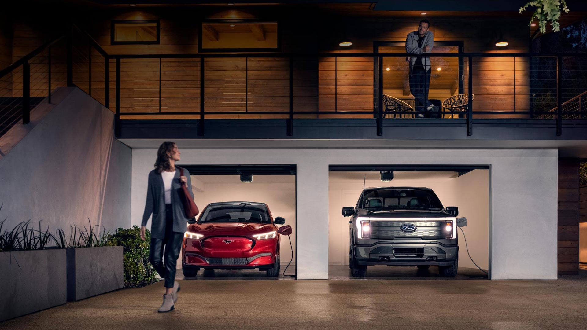 Woman walking out from home garage with a 2024 Mustang® Mach-E and Ford Lightning® truck in plugged-in and charging | Koons Ford Silver Spring in Silver Spring MD