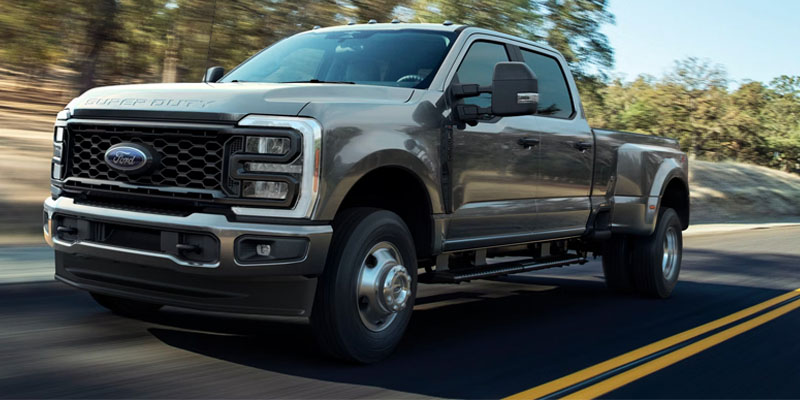 Gray Ford Super Duty pickup truck driving on a forest road